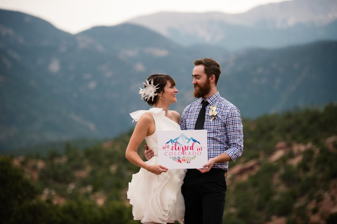 bride and groom holding pink and blue elopement sign