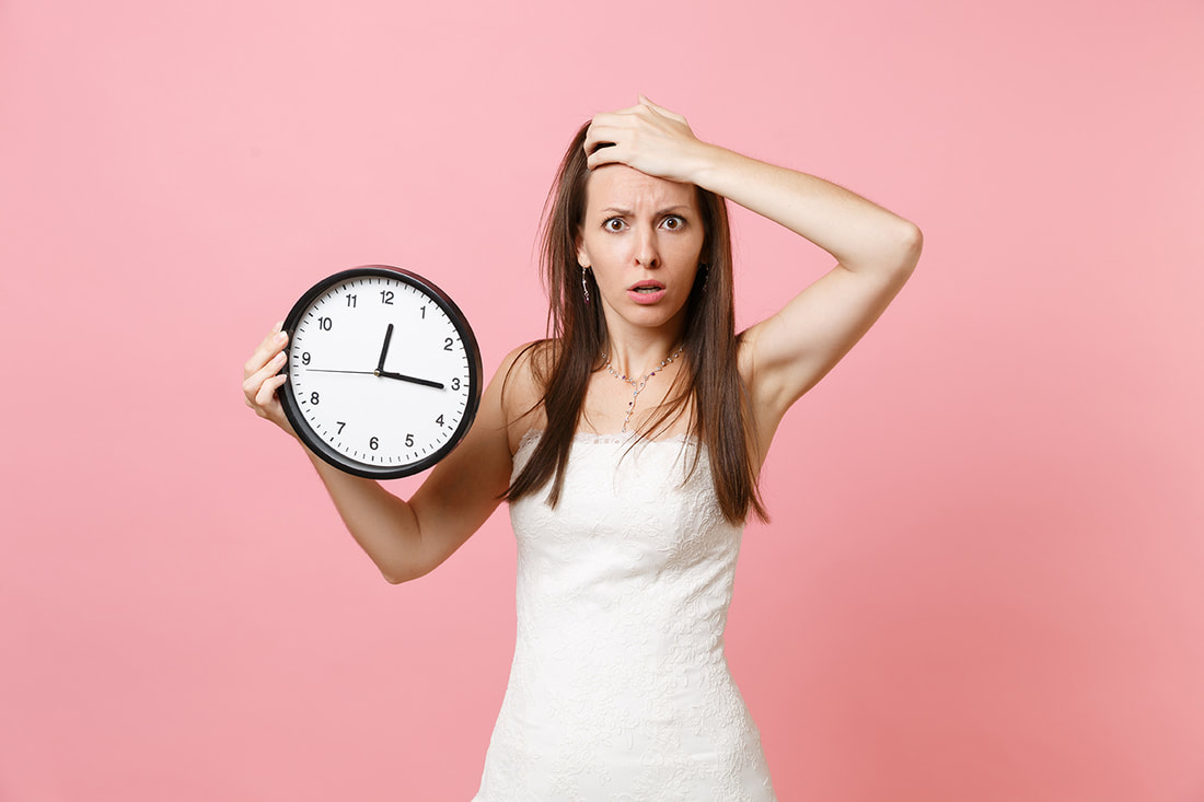bride in white dress holding a clock and pink background